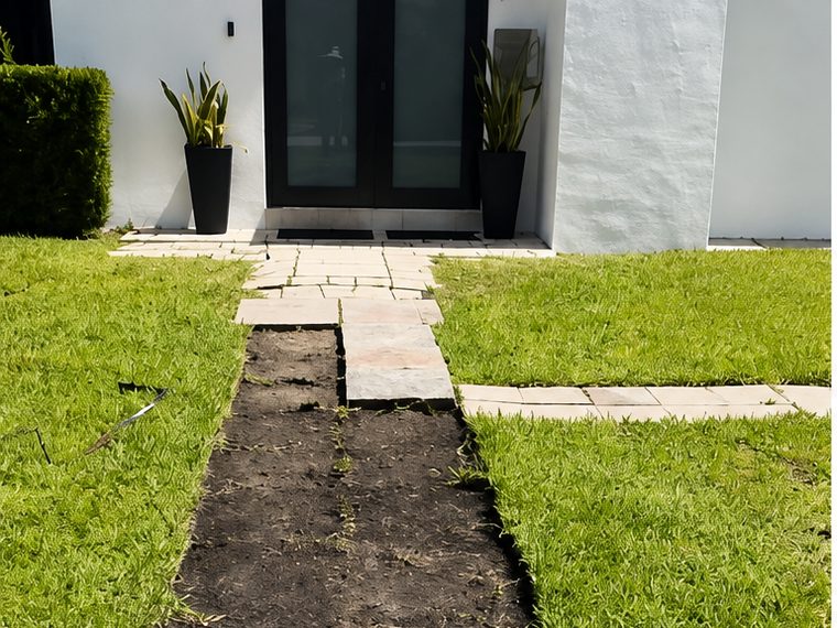 Before: a stripped dirt strip and loose stone slabs leading to the black french doors of a white house.