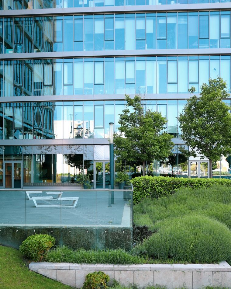 Business park entrance with a mown lawn, shaped shrubs, and a clean bed edge.