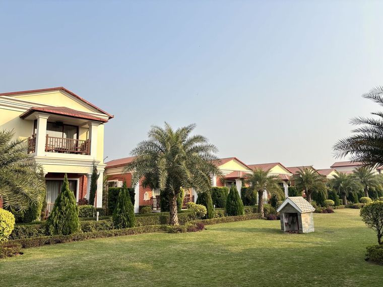 A residential community of tile-roofed units bordered by clipped hedges, palms and a wide mown lawn.
